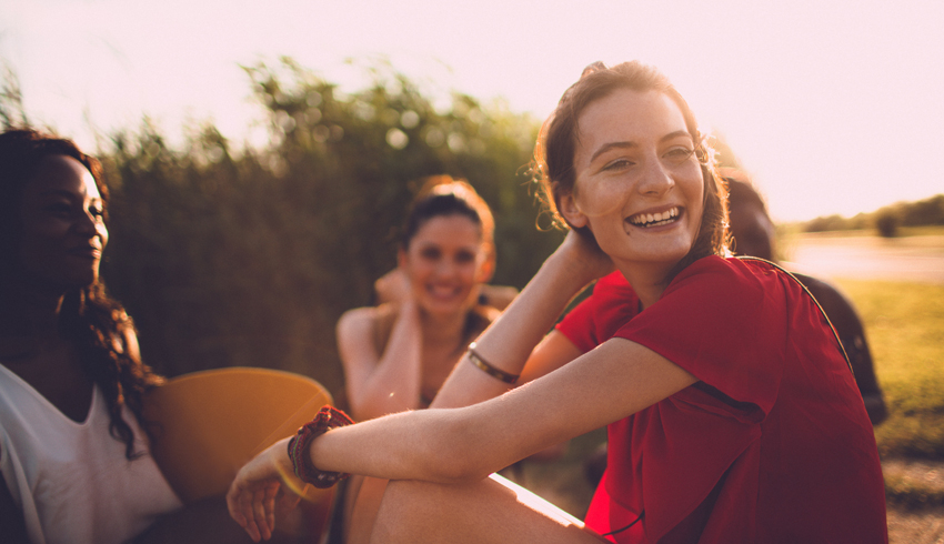 A smiling woman sitting with a group of friends outside